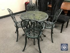 A cast metal patio table with parasol and four armchairs