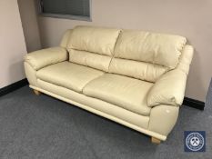 A cream leather two seater settee with oversized footstool