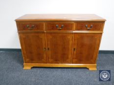An inlaid yew wood triple door sideboard