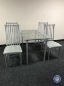 A contemporary metal and glass topped table with four chairs