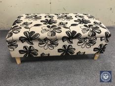 A contemporary floral upholstered footstool