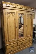 A carved pine triple door wardrobe fitted with five drawers,