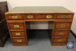 A reproduction twin pedestal campaign style writing desk with tooled leather top, width 121 cm.