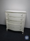 A cream and gilt serpentine fronted five drawer chest