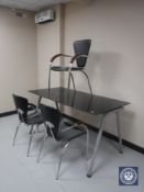 A glass topped desk on metal base and three armchairs