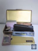 A table cigarette box containing playing cards, lighters,