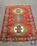 A Caucasian design rug on red ground, 186 cm x 122 cm.