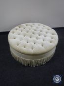 A large circular footstool in buttoned dralon