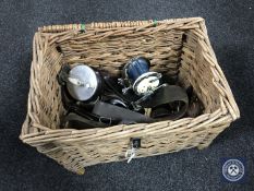 A wicker fishing basket of assorted reels including a Garcia Mitchell 624 reel,