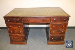 A late Victorian mahogany twin pedestal desk fitted with nine drawers and tooled leather top,