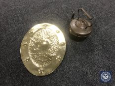 An oval brass Arts and Crafts plaque together with an antique copper kettle