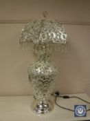 A highly ornate white metal and crystal drop table lamp with revolving shade.