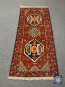 A Persian fringed rug on red ground,