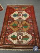 A Persian fringed rug on red ground,