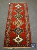 A Persian fringed rug on red ground,