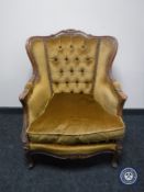 A 20th century carved wood framed armchair in gold button fabric
