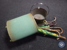 A green loom glass topped linen basket containing shooting sticks, walking sticks,