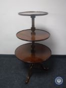 A mahogany three-tier dumb waiter on three-way pedestal
