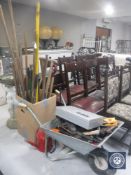 A wheel barrow containing hand tools, garden tools, drill,