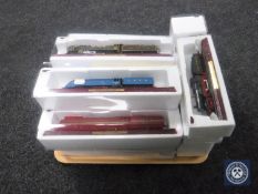 A tray containing eighteen scale model trains on wooden stands