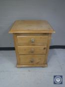 A stripped pine three drawer bedside chest