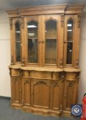 A heavily carved pine serpentine fronted glazed bookcase, width 155 cm.
