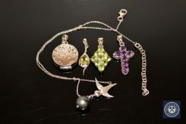 A silver and amethyst crucifix pendant, two silver peridot pendants,