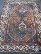 A fringed Persian woollen rug of geometric design