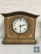 An inlaid oak cased mantel clock with pendulum
