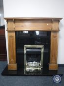 A pine fire surround with black granite inset and hearth and a brass framed fire