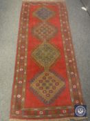 A fringed Caucasian design runner on red ground,
