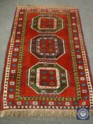 A fringed Caucasian design rug on red ground,