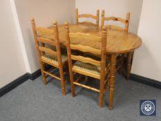 An oval pine extending table and four rush seated chairs