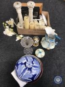 A box containing framed pictures, wooden candlesticks, clock under shade, ornaments,