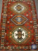 A fringed Caucasian design rug on red ground,