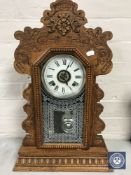 A carved oak American Ansonia Clock Company mantel clock with pendulum