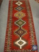 A fringed Caucasian design runner on red ground,