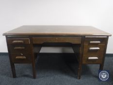 A mid 20th century oak desk fitted seven drawers