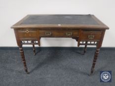 An Edwardian leather topped writing desk fitted three drawers