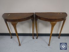 A pair of walnut D-shaped pie crust edge hall tables