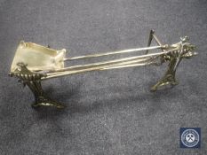 A pair of Art Nouveau brass fire dogs and a three piece fire companion set