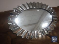 A contemporary oval sun burst all glass mirror
