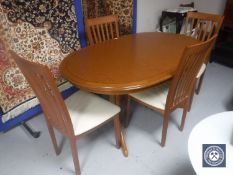 A teak G Plan oval extending table and four rail back chairs
