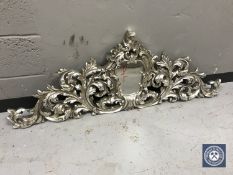 An ornate silver frieze panel with mirror