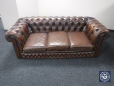 A brown buttoned leather Chesterfield three-seater settee together with a similar armchair