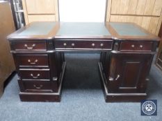A reproduction mahogany partner's desk with three green leather inset panels (one door missing)