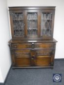 A carved oak triple door kitchen dresser fitted cupboards and drawers beneath
