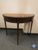 An Edwardian mahogany demi lune card table with green baize interior, width 84 cm.