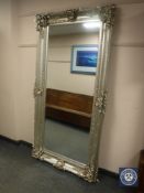 An ornate silvered floor-standing mirror,