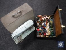 A cased Singer sewing machine and a briefcase of threads